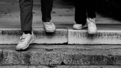 Artistic black and white shot of two people stepping down stairs with sneakers.